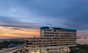 a hotel building with a sunset in the background at Hilton Shanghai Hongqiao International Airport in Shanghai