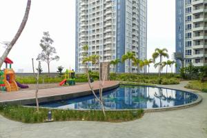 a playground with a pool in a city with tall buildings at Minimalist and Comfort Studio Podomoro City Deli Medan Apartment By Travelio in Medan