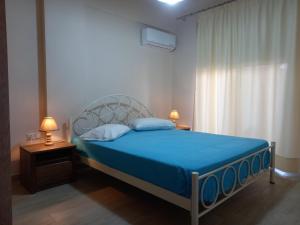 a bedroom with a blue bed with two lamps and a window at Makarounis Athanasios Apartments in Petalidi