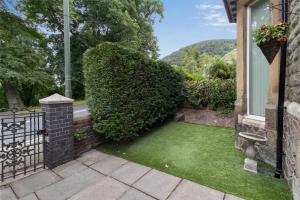 a yard with green grass next to a building at Elegant Malvhina Retreat on the Malvern Hills in Great Malvern