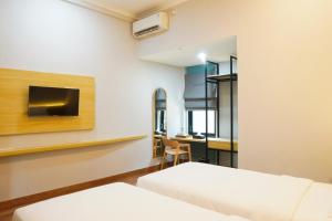 una habitación de hotel con dos camas y un escritorio en Ardiana Suite Hotel By Sajiwa, en Pangenjurutengah