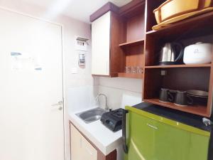 Una pequeña cocina con fregadero y estufa. en Modern Look and Homey Studio Amartha View Apartment By Travelio, en Semarang