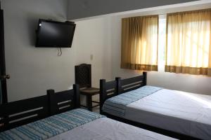 a bedroom with two beds and a flat screen tv at Hotel Calle8 in Tuxtla Gutiérrez