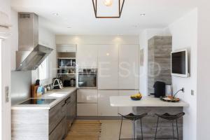 a kitchen with white cabinets and a counter with stools at Villa de vacances 5 chambres piscine privée et vue mer panoramique in Mandelieu-la-Napoule