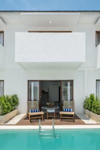 a house with a swimming pool with two chairs and a table at Baliterraneo Boutique Resort in Seminyak