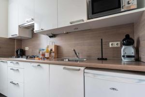 a kitchen with white cabinets and a sink at Hello Zeeland - Apartment Noordstraat 30 in Zoutelande +16 photos
