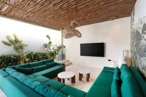 een woonkamer met groene meubels en een flatscreen-tv bij D'Palm Boutique Hotel - Uluwatu by Yolla Hospitality in Uluwatu