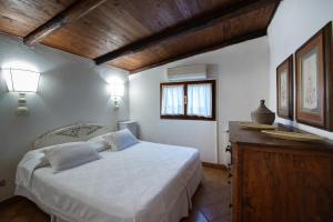 Un dormitorio con una cama blanca y un techo de madera. en Porto Ercole Prestige Villa, en Cala Galera