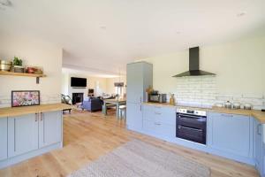 a large kitchen with blue cabinets and a living room at Contemporary Cottage & Garden in Dorset in Blandford Forum