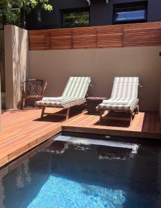 Dos sillas sentadas en una terraza junto a una piscina. en Rose Cottage, en Ciudad del Cabo 58 fotos más