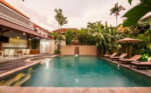 a swimming pool in a house with chairs and an umbrella at 6-BR Private Pool Legian Villa 5-min Walking to Beach in Seminyak