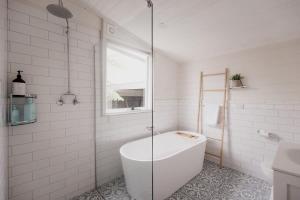 ein weißes Badezimmer mit Badewanne und Fenster in der Unterkunft Workers cottage on Wellington in Hobart + 29 Fotos