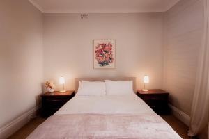 ein Schlafzimmer mit einem großen Bett mit zwei Lampen an Tischen in der Unterkunft Workers cottage on Wellington in Hobart