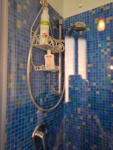 W wyłożonej niebieskimi kafelkami łazience znajduje się prysznic z wężem. w obiekcie Bed And Breakfast Loriana w Arezzo