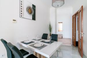 a white dining room with a white table and green chairs at Veoapartment Zaragoza in Seville