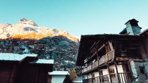 a snow covered mountain in the background of a building at Casalpina Cozy chalet in Gressoney-la-Trinité