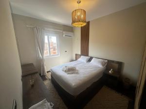 a bedroom with a bed with white sheets and a chandelier at Hotel Apartment New Cairo in Cairo