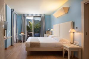 a bedroom with blue walls and a bed and a window at Hotel Kristal Palace - Tonelli Hotels - Adult Friendly in Riva del Garda