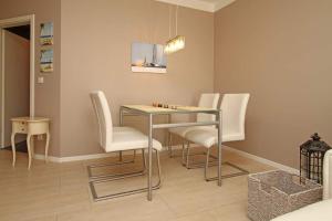 ein Esszimmer mit einem Glastisch und weißen Stühlen in der Unterkunft Weiße Düne, App. 03 in Ahlbeck