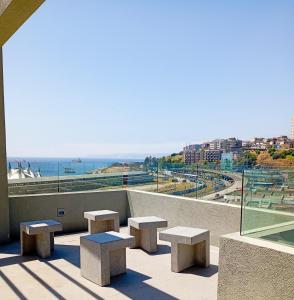 a group of benches sitting on a balcony overlooking the ocean at Disfruta de Valparaiso in Valparaíso