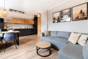 a living room with a blue couch and a kitchen at Apartament Dream View SPA in Szklarska Poręba