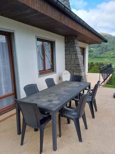 a black table and chairs in front of a house at La colline de pam in Cornimont