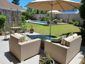 a patio with two chairs and an umbrella at Cottage@Somerset in Somerset West