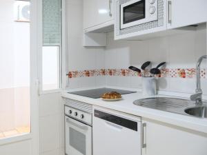 Una cocina blanca con fregadero y microondas. en TAYP San Marcos 104, en Talayuela