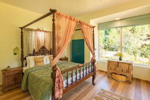 une chambre avec un lit à baldaquin et une fenêtre dans l'établissement Hollyhock Cottage by VEO - Part of StayVista, à Rāmgarh