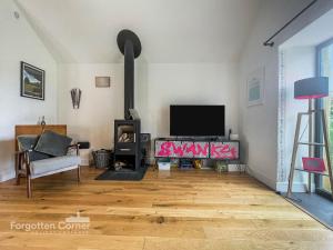 a living room with a tv and a wood stove at Wiggle Barn in Torpoint