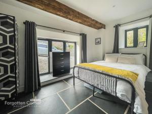 a bedroom with a bed and a dresser and windows at Wiggle Barn in Torpoint