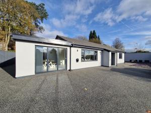 ein weißes Haus mit großen Fenstern auf einer Auffahrt in der Unterkunft Modern & Spacious 5 Bedroom Bungalow with Parking Near Brecon Beacons & Bike Park Wales in Cefn-coed-y-cymmer
