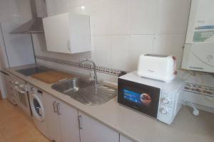 una cucina con lavello e microonde di Apartamento con 3 dormitorios y plaza de garaje a Tudela de Duero Altre 12 foto