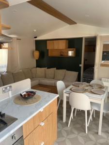 莱马特Mobil home climatisé 6,8 Pers SIBLU BONNE ANSE PLAGE LA PAMYRE LES MATHES的配有桌子和沙发的厨房和客厅