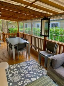 莱马特Mobil home climatisé 6,8 Pers SIBLU BONNE ANSE PLAGE LA PAMYRE LES MATHES的带桌椅的封闭式门廊