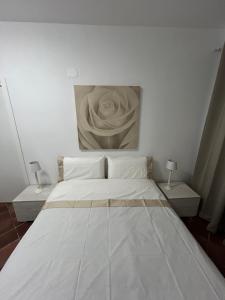 a bedroom with a white bed with a painting on the wall at Fly & Stay Apartments Fiumicino in Fiumicino