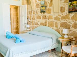 a bedroom with a bed with a blue teddy bear on it at Nuffara - a charming traditional Farmhouse with a large pool in Xagħra