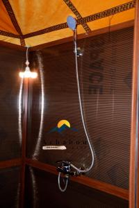a shower in a bathroom with a sign on the wall at Sahara Luxury Camp - Nuit de rêve dans le désert de Merzouga ! in Merzouga
