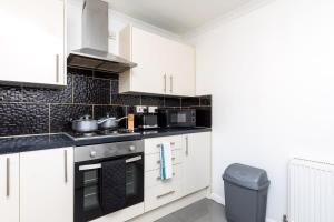 a kitchen with white cabinets and a trash can at 19A The Broadwalk - Cozy 1BR in the Heart of Crawley near GATWICK Airport great for contractors and flight crew students in Crawley +19 photos