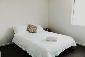 a white bed with two pillows and a book on it at Spacious Stay On Shamrock, Bendigo in Golden Square