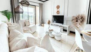 een woonkamer met witte meubels en een televisie bij Tropical Oasis-Luxury Apartment in Sandton