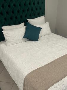 a bed with a green headboard and white sheets and pillows at Safaya Inn in Kempton Park