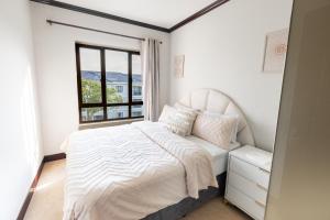 een witte slaapkamer met een bed en een raam bij Tropical Oasis-Luxury Apartment in Sandton +9 foto's