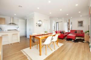 a kitchen and living room with a wooden table and chairs at Northside Townhouse Geelong in Norlane
