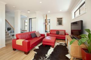 a living room with two red couches and a tv at Northside Townhouse Geelong in Norlane
