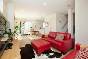 a living room with a red couch and a table at Northside Townhouse Geelong in Norlane +8 photos