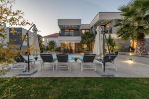 a group of chairs and umbrellas in front of a building at Villa Nina ZadarVillas in Zaton