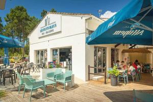 Un grupo de personas sentadas en mesas afuera de un restaurante. en Camping 4 étoiles - Piscine - eei0fg, en La Faute-sur-Mer