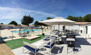 a pool with chairs and tables and an umbrella at Camping 4 étoiles - Parc aquatique - eeia0i in Le Bois-Plage-en-Ré