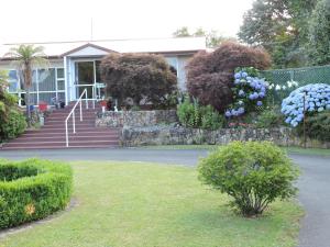 a house with a bunch of flowers in a yard at Maple Lodge Motel in Matamata